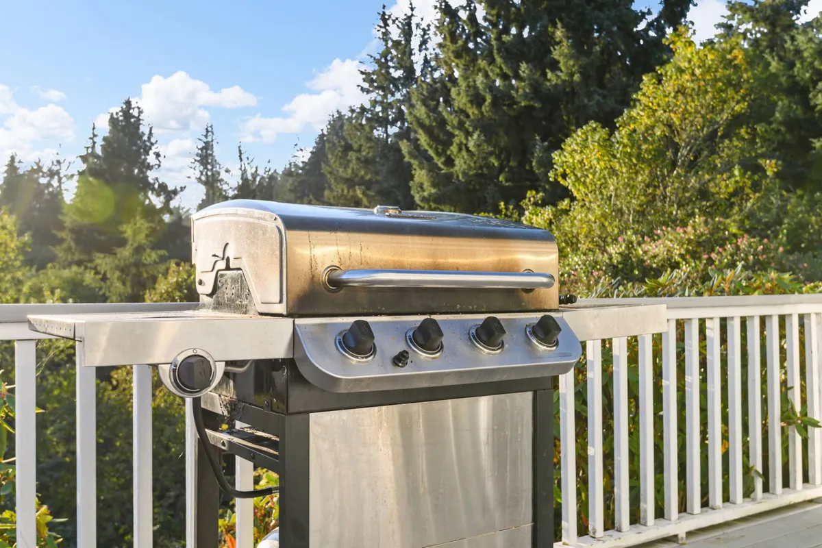 An exterior shot featuring a grill situated on a deck or patio with lush greenery beyond. The setup is ideal for outdoor dining, barbecues, and relaxed social gatherings after a day of adventure.