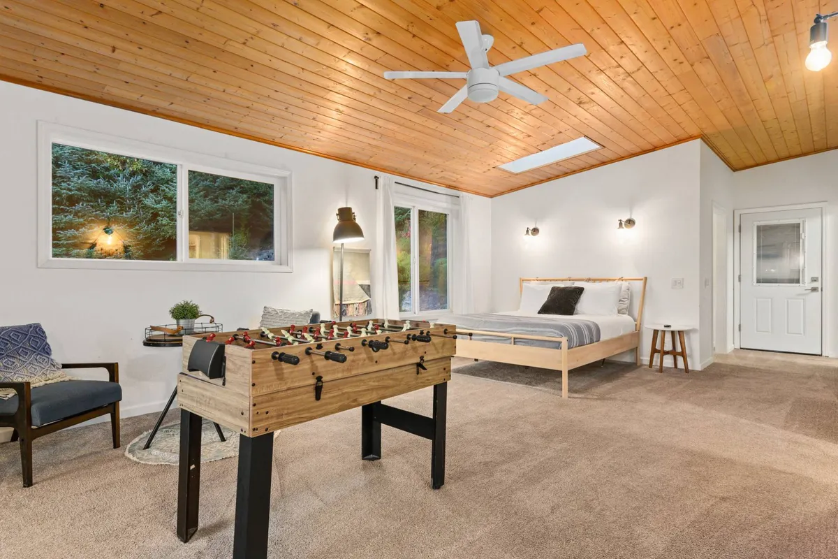 A playful, family-friendly room with a foosball table, a bed, and large windows that fill the space with light. The room is designed for both fun and relaxation, making it ideal for gatherings, game nights, or quiet mornings.